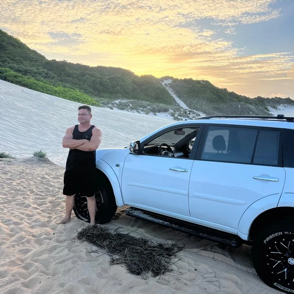Guia da Beiramar ao lado do 4x4 branco nas dunas, no pôr do sol