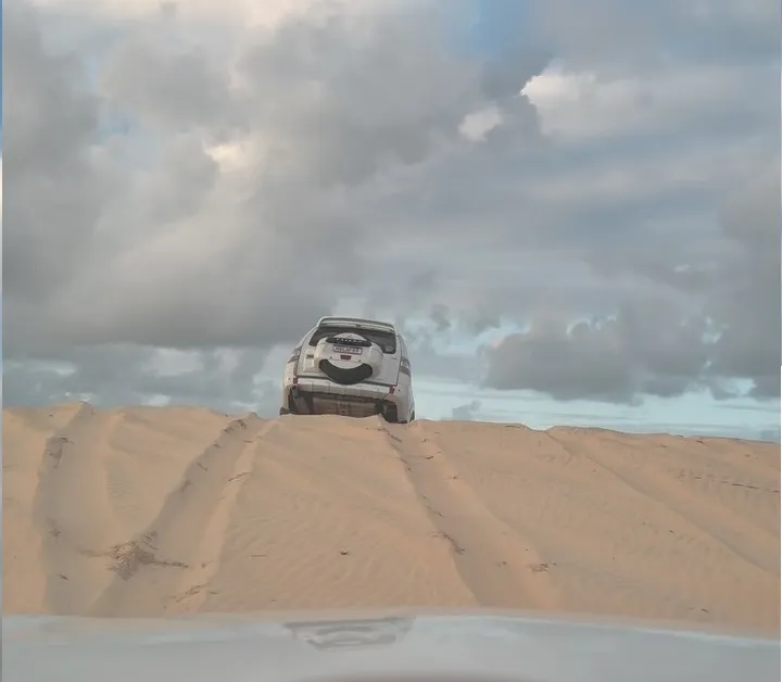 4x4 no topo da duna, visto de trás, sob um céu nublado